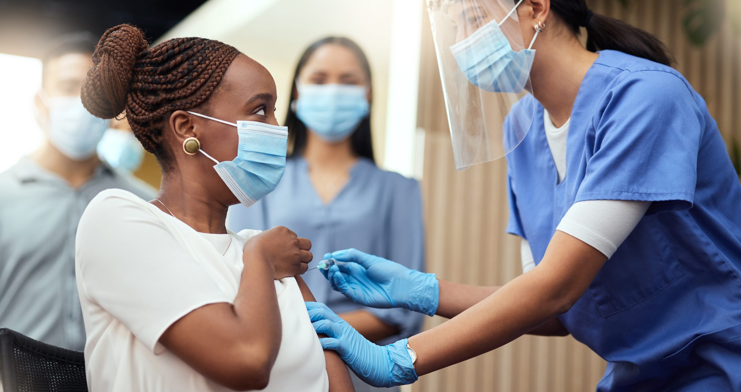 Cropped shot of an attractive young businesswoman getting her covid vaccination from a female nurse in the office
